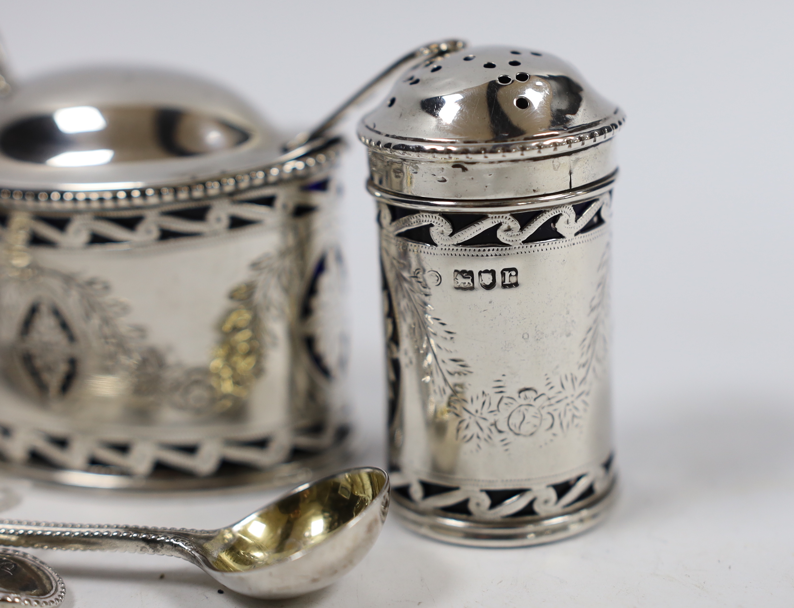 A George V pierced silver oval three piece cruet set and one spoon, Goldsmiths & Silversmiths Co Ltd, London, 1912, two Victorian silver condiment spoons and a sterling pepperette.